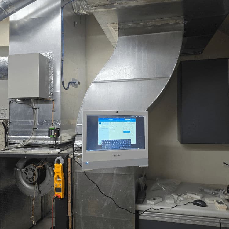 Control panel with computer monitor in HVAC system, showcasing ducts and tools.