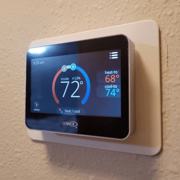 Smart thermostat display showing current temperature and settings on a wall.