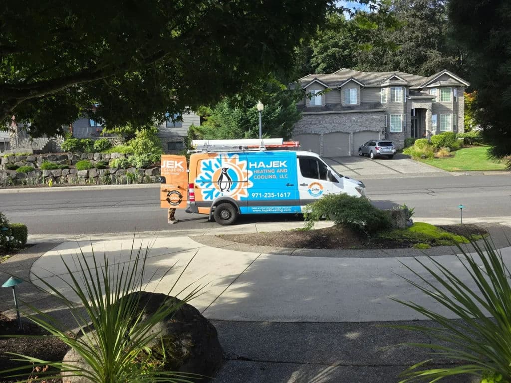 Hajek Heating and Cooling van parked in residential area with lush landscaping.