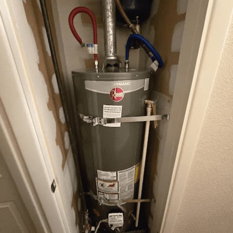 Rheem Performance water heater installed in a utility closet with visible pipes and fittings.