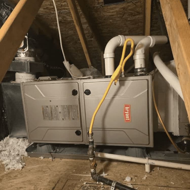 Residential attic furnace with yellow gas line, plumbing, and insulation in background.
