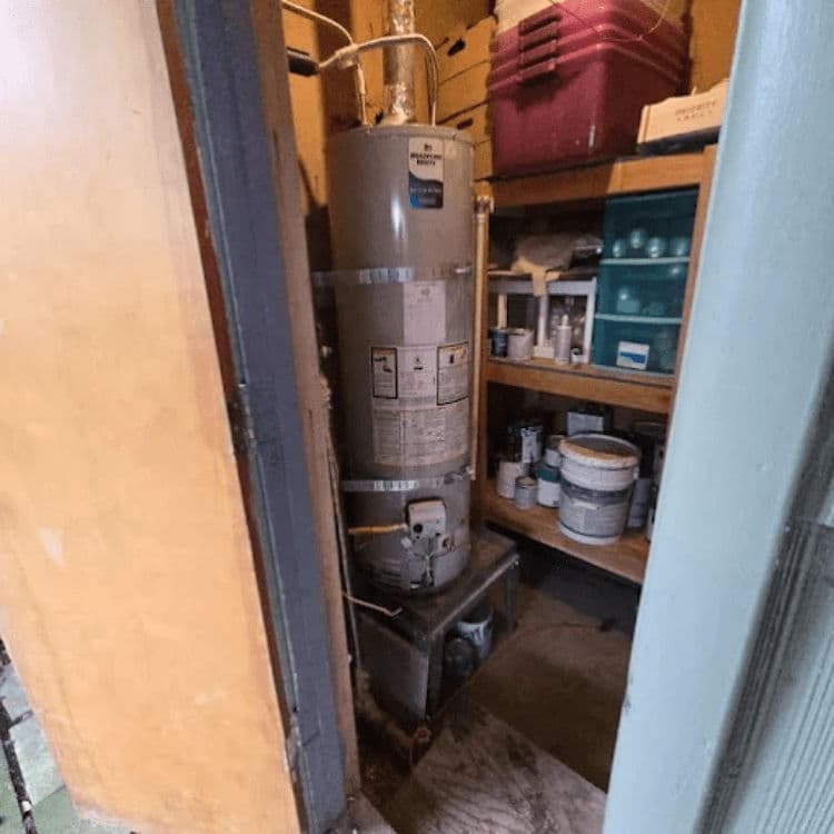 Water heater in a storage room with organized supplies and shelves.