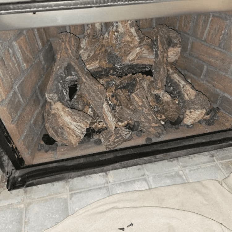 Cozy fireplace with arranged firewood and a soft beige rug in front.