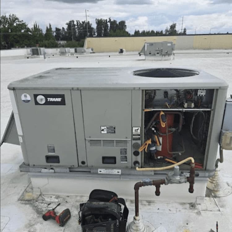 Trane rooftop HVAC unit with tools for maintenance and clear sky in the background.