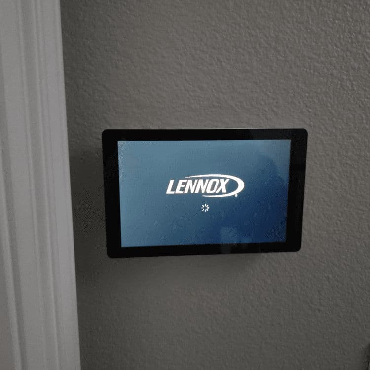 Lennox smart thermostat displaying startup screen on a wall-mounted panel.