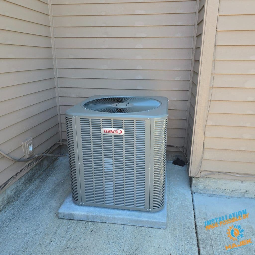 Lennox air conditioning unit installed on concrete slab next to beige siding.