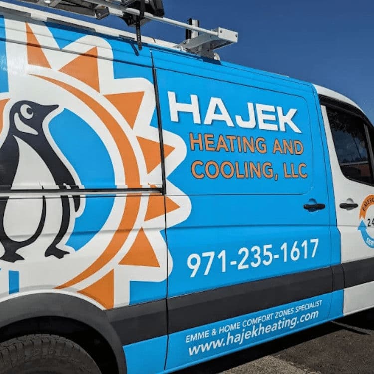 Hajek Heating and Cooling van with penguin logo, bright blue design, and contact info.