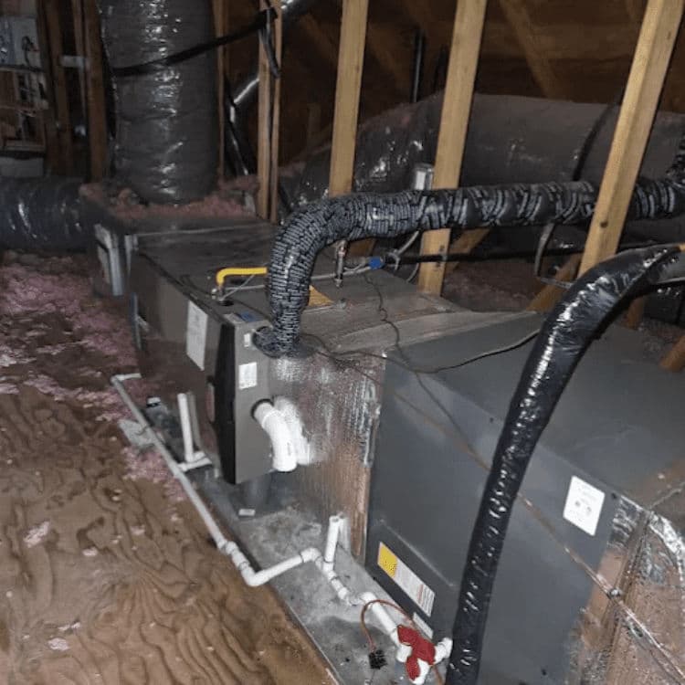 HVAC system installation in an attic with ducts and insulation visible.