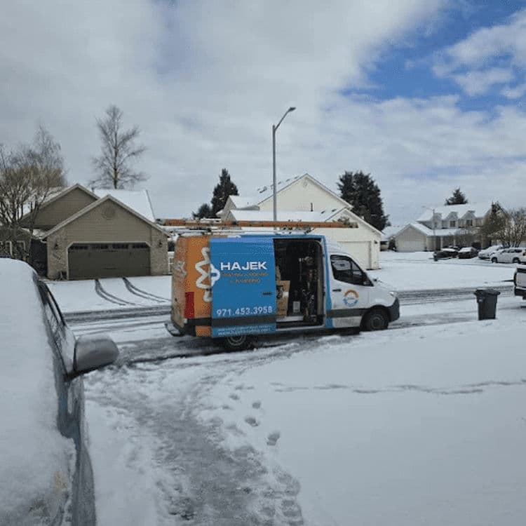 Service van in snowy residential area, featuring Hajek branding and contact information.