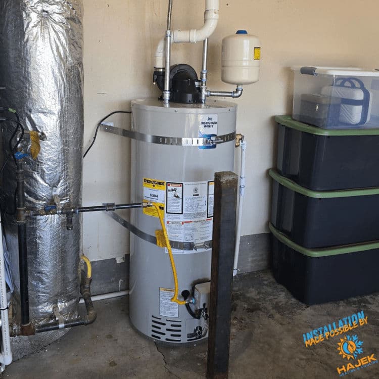 Newly installed water heater with insulated piping in a garage setting.
