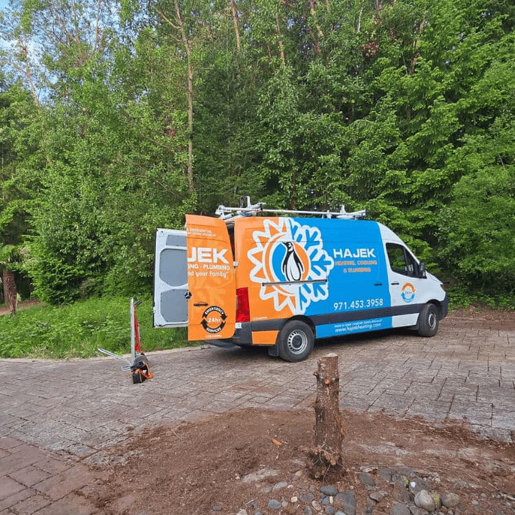 Hajek service van parked in a green area, showcasing plumbing and electrical branding.