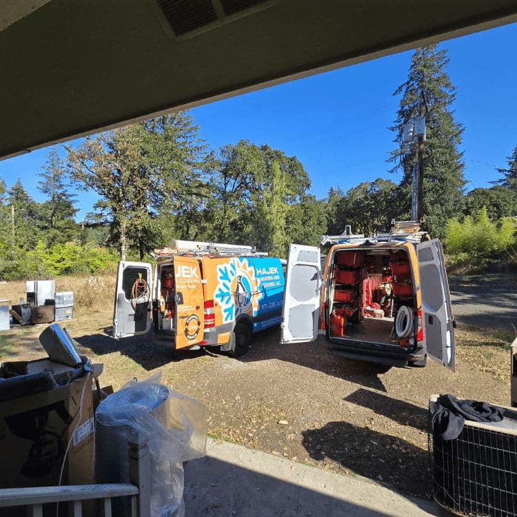 Service vans with open doors parked outdoors, surrounded by trees and equipment.
