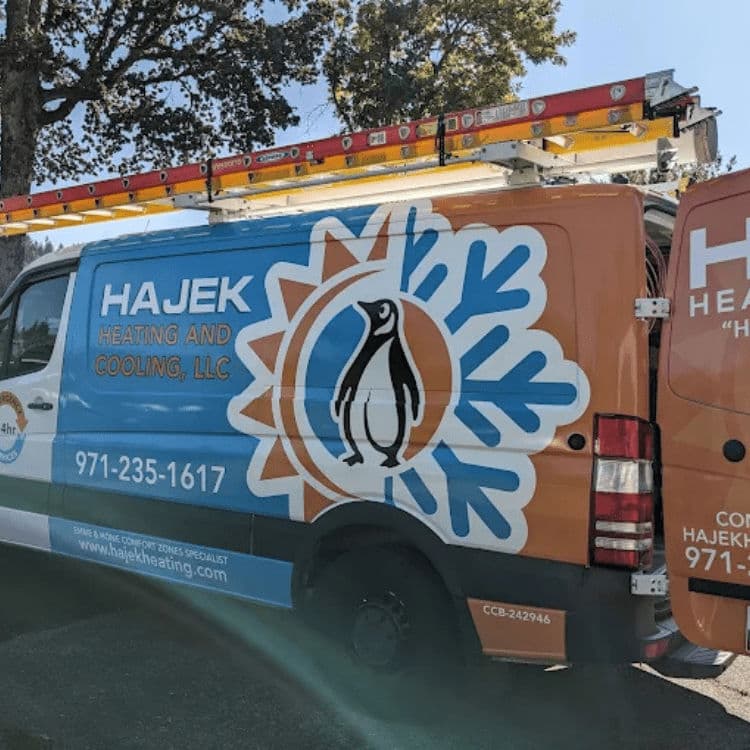 Hajek Heating and Cooling van with penguin logo parked outdoors for HVAC service.
